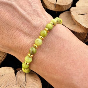 Peut inclure: Un bracelet en perles vertes et dorées avec des entretoises dorées. Le bracelet est composé de perles rondes et est porté au poignet.