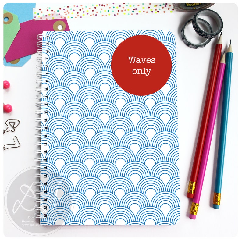 May include: A white spiral bound notebook with a blue and white wave pattern on the cover. A red circle with the text "Waves only" is on the front cover.