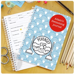 May include: A blue and white spiral bound notebook with a swimming themed cover. The cover features a swimmer in a circle with the text "Pevensey Plungers". The notebook also has the text "Adam's Swimming Journal" in a red circle.