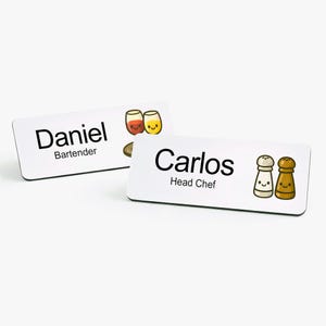 May include: Two white name tags with rounded corners. One tag reads "Daniel" and "Bartender" in black text, with cartoon drink illustrations. The other tag reads "Carlos" and "Head Chef" with cartoon salt and pepper shaker illustrations.