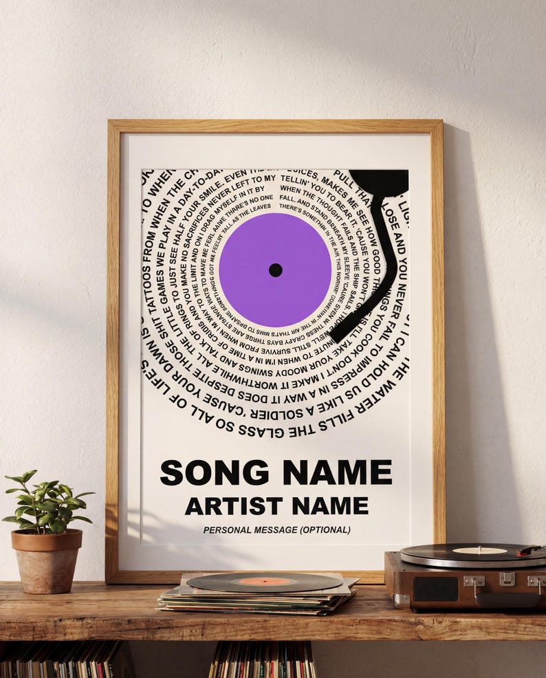 May include: A framed print featuring a stylized vinyl record design. The record is purple with a black center and surrounded by song lyrics in a circular pattern. The print includes the text "SONG NAME", "ARTIST NAME", and "PERSONAL MESSAGE (OPTIONAL)".