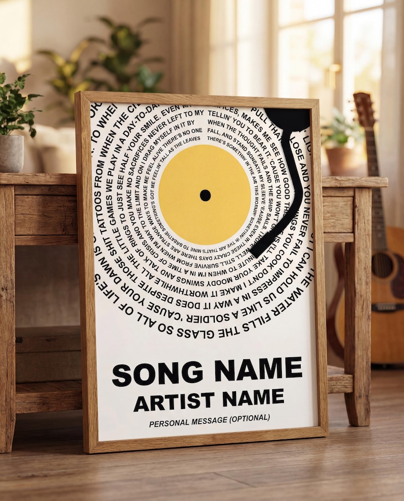 May include: Framed print with a yellow vinyl record design and song lyrics in a circular pattern. It has space for a song name, artist name, and a personal message. The frame is a light brown colour.
