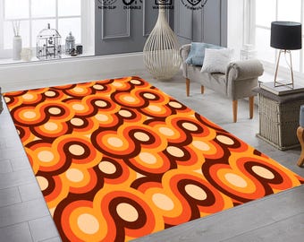May include: A rectangular area rug with a retro design. The rug features a repeating pattern of orange, brown, and cream-colored circles. The rug is placed on a light gray wooden floor.