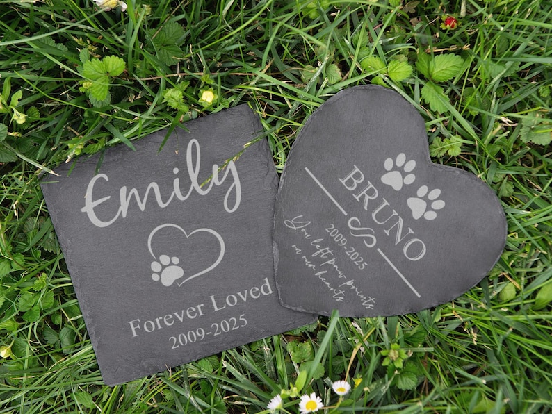 Puede incluir: Dos piedras conmemorativas para mascotas de pizarra. Una cuadrada con "Emily" y un coraz&oacute;n con huella de pata, la otra en forma de coraz&oacute;n con "Bruno" y huellas de pata. Ambas tienen fechas y el texto "Forever Loved" y "You left paw prints on our hearts".