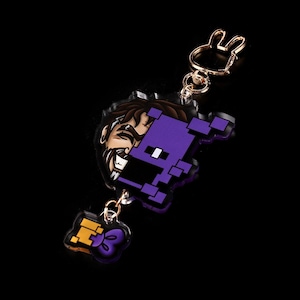 May include: Purple and gold pixelated character keychain with a cartoon face and a gold bunny charm.
