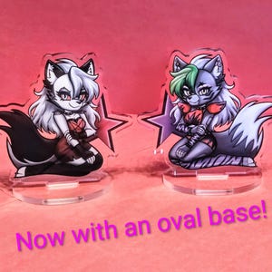 May include: Two acrylic character stands featuring cartoon wolf characters with white, black, and gray fur, and red and black outfits. Each stand is on a clear oval base, with a star-shaped background. The text "Now with an oval base!" is at the bottom.