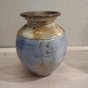 May include: A small, blue and brown ceramic vase with a rounded body and a flared rim.