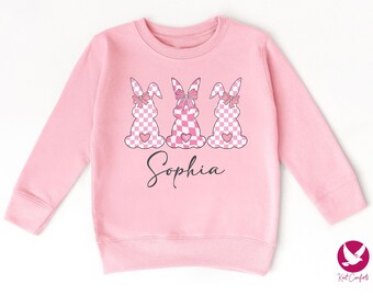 May include: Pink children's sweatshirt with three pink and white checkered bunnies wearing pink bows. The sweatshirt has the name "Sophia" printed on the front.