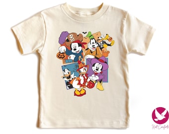 May include: Cream-colored t-shirt featuring a Halloween-themed graphic of Disney characters, including Mickey Mouse, Goofy, Donald Duck, and Minnie Mouse, in costumes. The design includes pumpkins and bats.