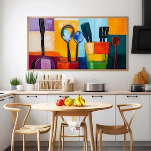 May include: Abstract art print featuring kitchen utensils in a colorful, geometric style. The artwork includes spoons, spatulas, and other tools against a backdrop of vibrant blocks of color, framed in a light wood.