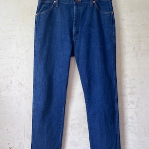 May include: A pair of blue denim jeans hanging on a clothes hanger. The jeans have a classic straight leg style and are made of a durable denim fabric.