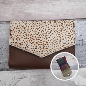 May include: A white ceramic mug with a black handle and the text "But First, Coffee" in a bold, black font. The mug is set against a blurred background, suggesting a cosy setting.