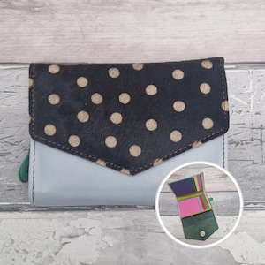 May include: A white ceramic mug with a black handle and the text "But First, Coffee" in a bold, black font. The mug is set against a blurred background, suggesting a cosy setting.