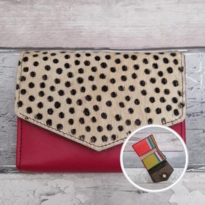 May include: A bi-fold wallet. The base is made of red leather, and the flap is beige with black polka dots. A small inset image shows the wallet's interior, with colourful card slots.