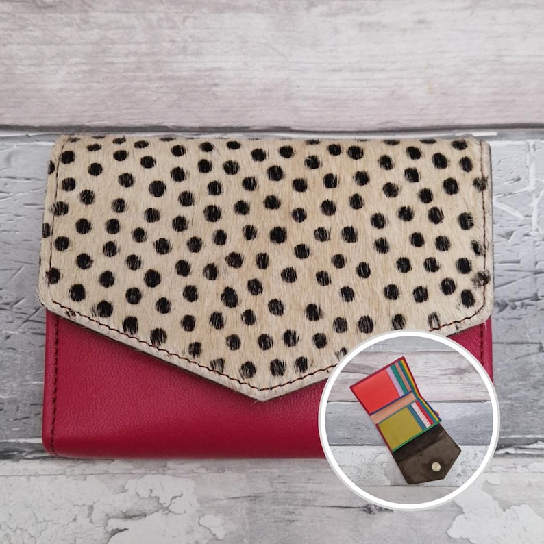 May include: A bi-fold wallet. The base is made of red leather, and the flap is beige with black polka dots. A small inset image shows the wallet's interior, with colourful card slots.