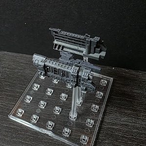 Puede incluir: Modelo detallado de nave espacial gris oscuro con diseños intrincados, montado sobre un soporte acrílico transparente. El modelo presenta múltiples niveles y estructuras, lo que sugiere un tema futurista o de ciencia ficción.