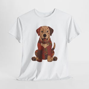 Op de afbeelding: Een wit t-shirt met korte mouwen en een centrale afbeelding van een zittende hond. De hond is weergegeven in een patchworkstijl met diverse tinten bruin, rood en beige, inclusief ruitjes, bloemmotieven en stippenpatronen.