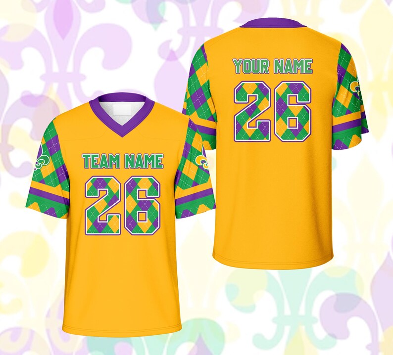 Op de afbeelding: Twee gele voetbalshirts met paarse en groene accenten. Het shirt aan de voorkant heeft "TEAM NAME" en het nummer "26" in groen. Het shirt aan de achterkant heeft "YOUR NAME" en het nummer "26". De mouwen hebben een ruitpatroon.