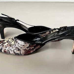 May include: A pair of black slingback heels with pointed toes. The toe area features a sequined pattern in shades of brown, beige, and silver. The heels are approximately 3 inches tall.