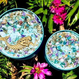 May include: Two teal blue round containers with lids, filled with blue, green, and purple crystals and a gold mermaid figurine in one container.