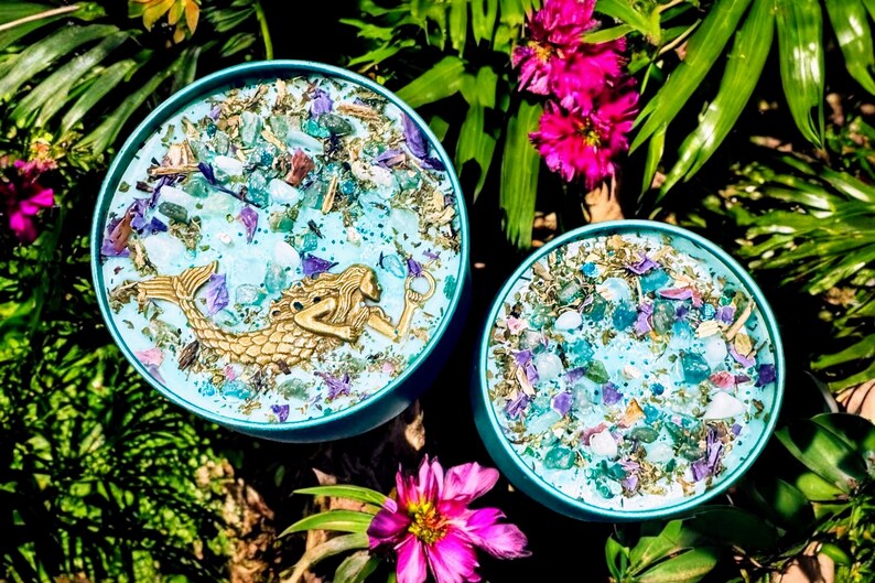 May include: Two teal blue round containers with lids, filled with blue, green, and purple crystals and a gold mermaid figurine in one container.