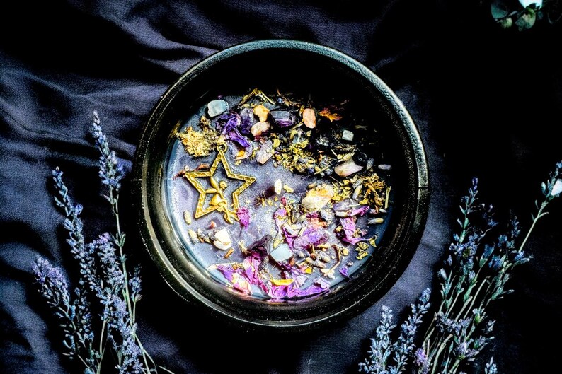 May include: A black bowl filled with dried herbs, flowers, and crystals. The bowl is surrounded by sprigs of lavender.