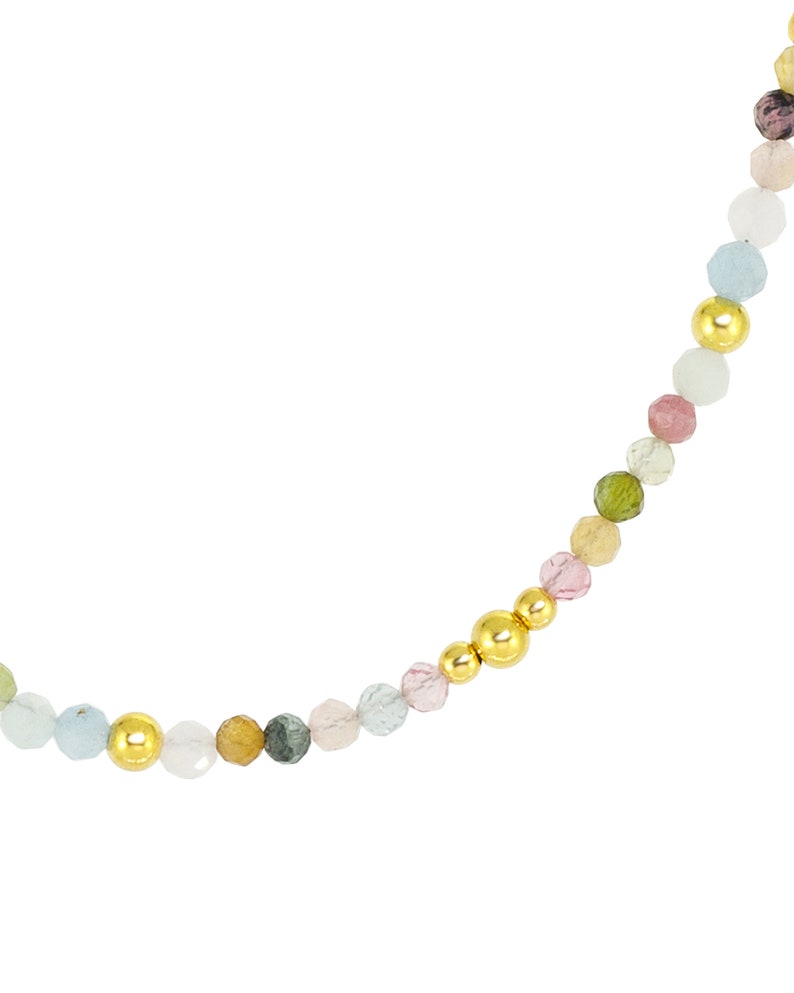 May include: A multi-colored gemstone beaded necklace with gold accents. The necklace features a variety of round, faceted gemstones in shades of pink, green, blue, and yellow.