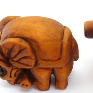 May include: Two small, intricately carved wooden elephant figurines. The elephants are brown and have detailed features, including eyes, ears, and trunks.