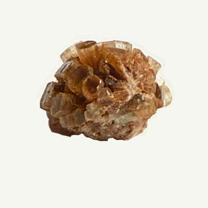 May include: A cluster of aragonite crystals, showcasing a warm, earthy palette of brown and tan hues. The crystals are clustered together, creating a textured, organic form. The mineral specimen is set against a plain white background.