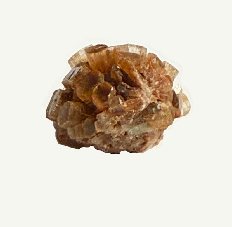 May include: A cluster of aragonite crystals, showcasing a warm, earthy palette of brown and tan hues. The crystals are clustered together, creating a textured, organic form. The mineral specimen is set against a plain white background.