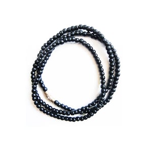 May include: A black beaded necklace with a silver clasp. The necklace is made of small, round beads and is approximately 18 inches long.