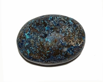 May include: A polished, oval-shaped stone with a mottled pattern of blue, brown, and tan hues. The stone's surface has a smooth, glossy finish, and the colors are distributed in a speckled, organic design. The stone is set against a white background.