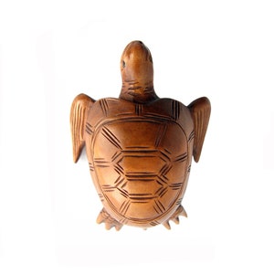 May include: A wooden turtle sculpture with a detailed carved shell. The turtle is brown and has a natural wood finish.