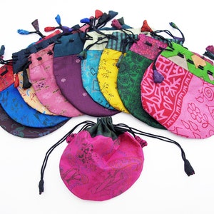 May include: A collection of 12 colorful drawstring pouches made from recycled silk fabric. Each pouch features a unique pattern and is perfect for storing small items like jewelry, coins, or trinkets.