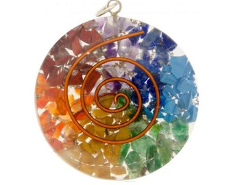 May include: A round, clear pendant with a copper wire spiral design. The pendant is filled with small, colorful gemstones in a rainbow pattern.