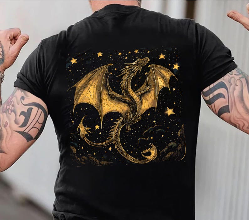 May include: Black t-shirt featuring a golden dragon design with outstretched wings, set against a starry night sky. The dragon is intricately detailed, with a long tail and detailed wings. The design includes stars and clouds.