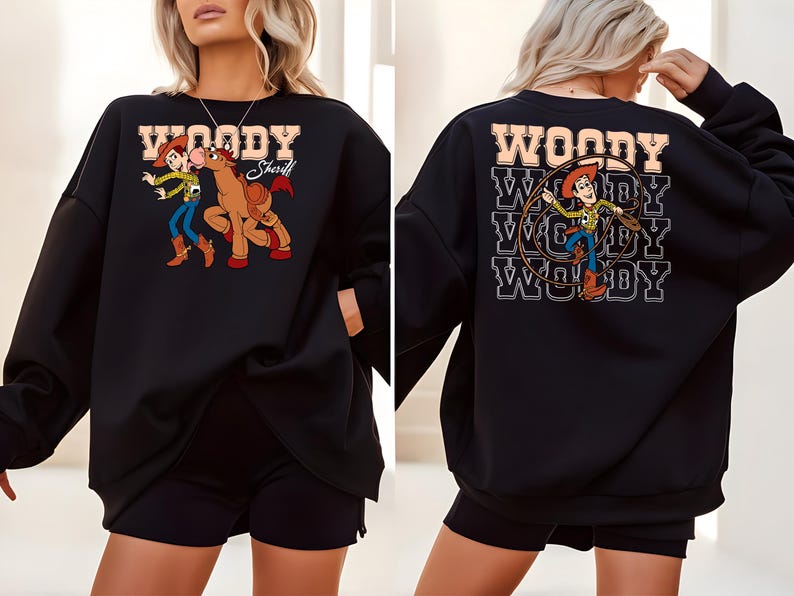 Puede incluir: Sudadera negra con un gr&aacute;fico de dibujos animados de Woody y un caballo. La parte delantera de la sudadera tiene la palabra "WOODY Sheriff" en una fuente marr&oacute;n. La parte trasera de la sudadera tiene la palabra "WOODY" repetida tres veces con un gr&aacute;fico de Woody.