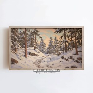 May include: A framed painting of a winter scene. The artwork shows a snow-covered path through a forest of pine trees. The sky has soft pink and orange tones. The text "BLUEBELL PRINTS Elegant Art Collective" is at the bottom.