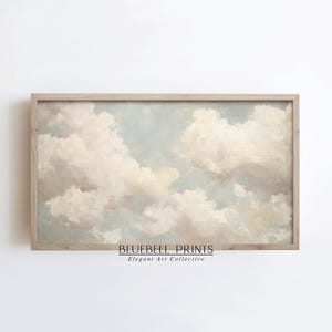 May include: A framed print of a painting depicting a cloudy sky in shades of white and light blue. The print is framed in a light wood frame and has the text "BLUEBELL PRINTS Elegant Art Collective" at the bottom.