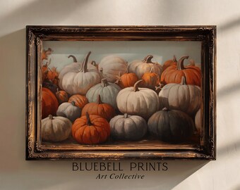 Puede incluir: Una impresión artística enmarcada que presenta una naturaleza muerta de calabazas de varios tamaños y colores, incluyendo blanco, naranja y gris. La obra de arte está ambientada sobre un fondo azul claro y enmarcada en un marco marrón oscuro y ornamentado. El texto "BLUEBELL PRINTS Art Collective" está en la parte inferior.