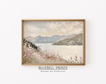 May include: A framed painting of a landscape with mountains, a lake, and pink flowers in the foreground. The sky is a soft blue with white clouds. The mountains are a muted green and brown. The lake is a light blue. The flowers are a soft pink. The frame is a gold color. The text "BLUEBELL PRINTS Elegant Art Collective" is at the bottom of the frame.