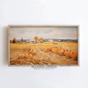 May include: A framed landscape painting depicting a rural autumn scene. The artwork features a field of golden wheat, orange pumpkins, and farm buildings under a cloudy sky. The text "BLUEBELL PRINTS Elegant Art Collective" is visible at the bottom.