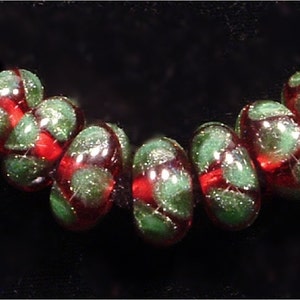 May include: A strand of red and green glass beads with a speckled finish. The beads are round and have a glossy finish.