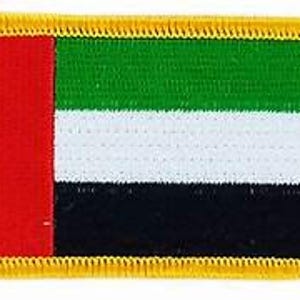 Op de afbeelding: Rechthoekige patch met de vlag van de Verenigde Arabische Emiraten. Het vlagontwerp omvat een verticale rode streep en horizontale strepen in groen, wit en zwart. De patch heeft een gouden rand.
