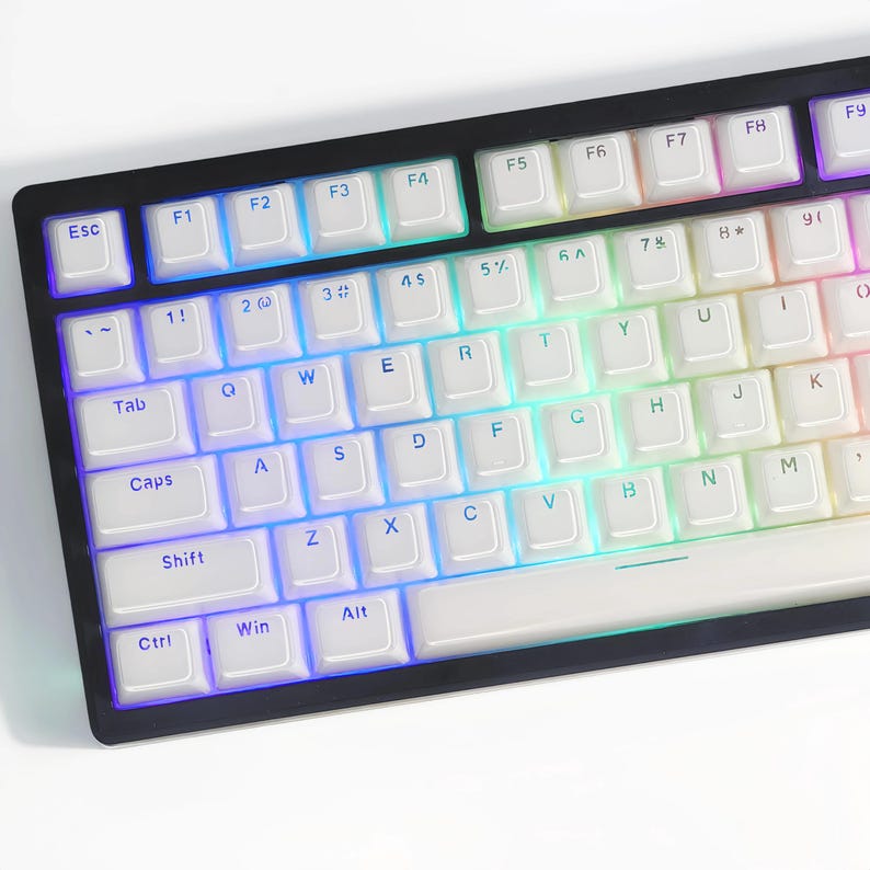 Op de afbeelding: Een wit mechanisch toetsenbord met regenboogkleurige LED-achtergrondverlichting. De toetsen hebben een witte achtergrond met zwarte letters. Het toetsenbord heeft een zwart frame en een witte spatiebalk.
