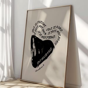 Op de afbeelding: Zwart-witte typografie kunstprint met een hartvorm en de tekst "Liefde is geduldig, ze is niet jaloers, ze is niet trots. Liefde is vriendelijk, ze is niet opschepperig, liefde faalt nooit. 1 Korintiërs 13"