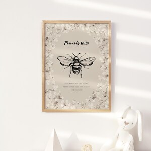 Pu&ograve; includere: Stampa artistica incorniciata con un'illustrazione di un'ape in bianco e nero, circondata da motivi floreali. La stampa include il testo "Proverbi 16:24" e una citazione. Un elemento decorativo per l'arredamento della casa.