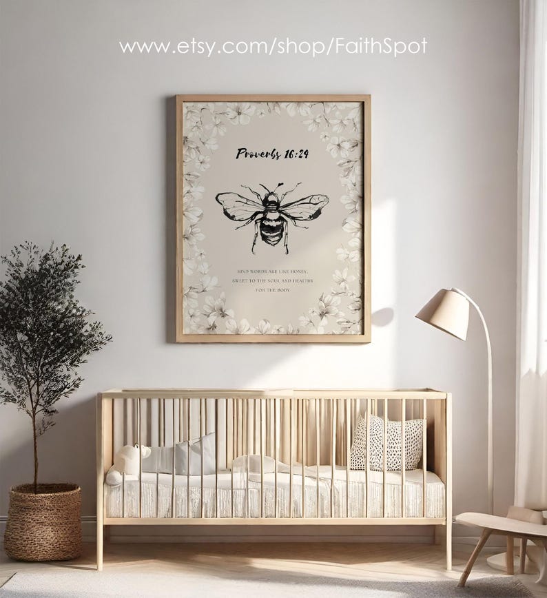 Pu&ograve; includere: Una stampa incorniciata con un'illustrazione di un'ape in bianco e nero e il testo "Proverbi 16:24". La stampa &egrave; circondata da un bordo floreale e appesa sopra una culla di legno. Un piccolo albero in un cesto intrecciato &egrave; a sinistra.