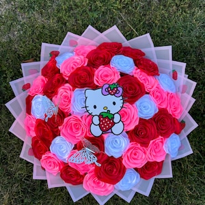 May include: A bouquet of pink, red, and white paper roses arranged in a pink and white paper basket. The roses are surrounded by a Hello Kitty character holding a strawberry.