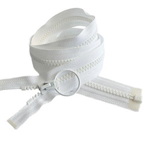 May include: A white zipper with a white slider and a white pull tab. The zipper is coiled up and ready to be sewn into a garment.